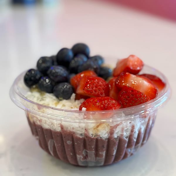 A vibrant acai bowl topped with fresh blueberries, sliced strawberries, and shredded coconut.